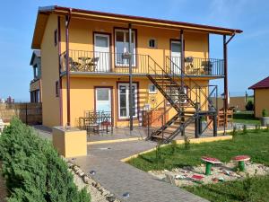 ein gelbes Haus mit einer Treppe davor in der Unterkunft La Toscana Costinești in Schitul