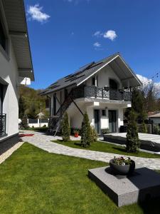 a white house with a vase in the front yard at Casa din Vale apartament - Valiug in Văliug