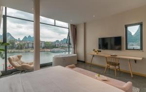 a hotel room with a bed and a desk and window at Xitang River View Holiday Motel in Yangshuo