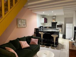 a living room with a couch and a kitchen at Petite maison agréable climatisée in Nègrepelisse