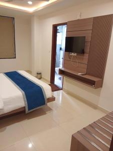 a bedroom with a bed and a flat screen tv at Hotel Garden View - Mansarovar in Jaipur