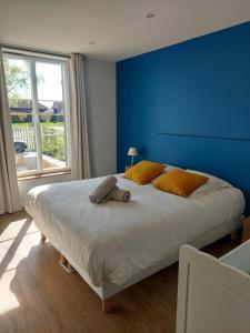 a bedroom with a large bed with a blue wall at Gite du domaine, au coeur d'une ferme en activité in Piney