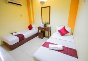 a room with two beds and a table with a mirror at Sun Inns Hotel Sunway Mentari in Petaling Jaya