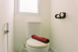 a red towel sitting on a toilet in a bathroom at Homey and Tidy Studio Room Aeropolis Apartment By Travelio in Tangerang +2 photos