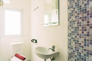 a bathroom with a sink and a toilet and a mirror at Homey and Tidy Studio Room Aeropolis Apartment By Travelio in Tangerang