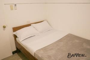 a bed with white sheets and pillows in a room at Bay View Inn in Surigao