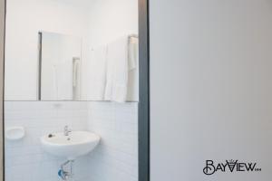 a white bathroom with a sink and a mirror at Bay View Inn in Surigao