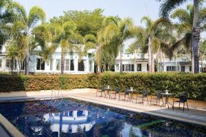 a pool with tables and chairs and palm trees at Villa Reina Resort in Nong Nam Daeng