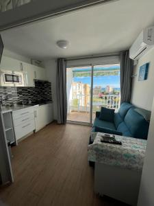 a living room with a blue couch and a kitchen at EL PISET in La Pineda