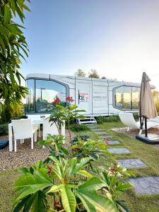 an rv parked in a yard with a table and chairs at Nx Space พลูวิลล่า in Nakhon Nayok