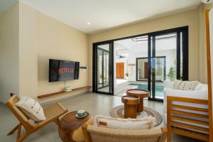 a living room with a couch and a tv at Villa Le Blanc in Tumbak Bayuh