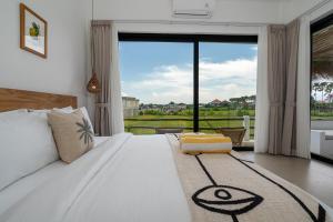 a bedroom with a white bed with a large window at Villa Le Blanc in Tumbak Bayuh