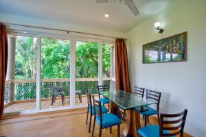 a dining room with a table and chairs and a large window at Aveeno Resort & Villas Near Calangute and Baga in Jāmb