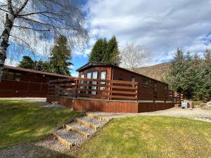 a large wooden cabin with stairs in front of it at Lodge 2 The Wee Hut Aviemore in Aviemore