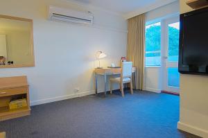 a hotel room with a desk and a television at Park Squire Motor Inn & Serviced Apartments in Melbourne