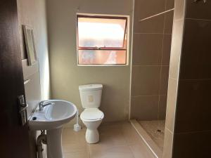 a bathroom with a toilet and a sink and a window at AS contractors accommodation in Erasmus