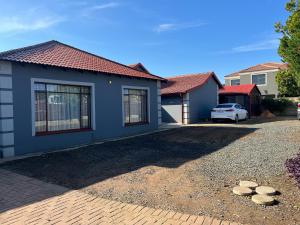 a blue house with a car parked in the driveway at AS contractors accommodation in Erasmus