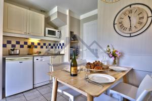 a kitchen with a table and a clock on the wall at LocaLise - Maison G4 au Guilvinec - A 50m de la mer avec jardin et piscine - Tout à pied, plages, port, centre, commerces, marché - Wifi inclus - Animaux bienvenus - Linge de lit inclus in Le Guilvinec