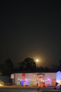 un bâtiment éclairé avec une lune dans le ciel dans l'établissement Happy Hippy Hub by Yatrimap, à Jāmb