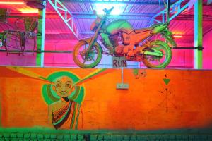 une moto garée au sommet d'un mur avec un tableau dans l'établissement Happy Hippy Hub by Yatrimap, à Jāmb