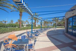 a patio with tables and chairs and palm trees at Patacona Resort Apartments Primera Linea in Valencia