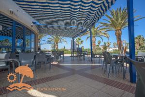 a restaurant with tables and chairs and palm trees at Patacona Resort Apartments Primera Linea in Valencia