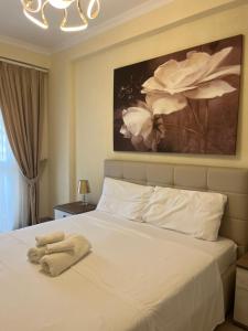 a bedroom with a white bed with a painting on the wall at Dea Luxury Apartament Beach in Durrës