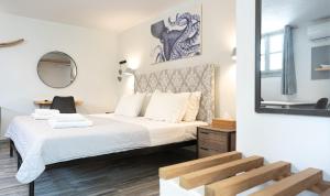a bedroom with a bed with white sheets and a mirror at WHITE W3 New studio in Naousa in Naousa