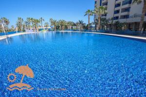 a large swimming pool with an umbrella in the water at Patacona Resort Apartments Primera Linea in Valencia