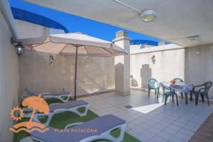a patio with a table and chairs and an umbrella at Patacona Resort Apartments Primera Linea in Valencia