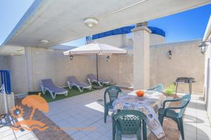 a patio with a table and chairs and an umbrella at Patacona Resort Apartments Primera Linea in Valencia