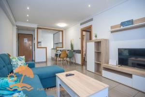 a living room with a blue couch and a tv at Patacona Resort Apartments Primera Linea in Valencia
