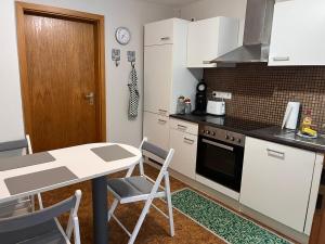 a kitchen with white cabinets and a table with chairs at Zu Gast bei Freunden in Weingarten (Karlsruhe)