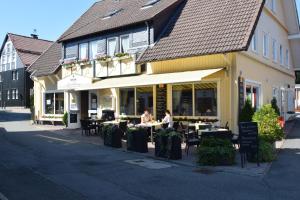 two people sitting at tables outside of a building at Cafe Steffens in Hahnenklee-Bockswiese