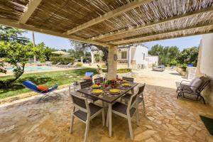 ein Esszimmer mit einem Tisch und Stühlen auf einer Terrasse in der Unterkunft Villa Agata Salentino by Villa Plus in San Michele Salentino
