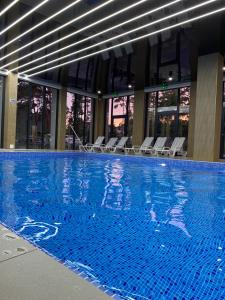 a large swimming pool with chairs in a building at Forest Apartment in Pobierowo