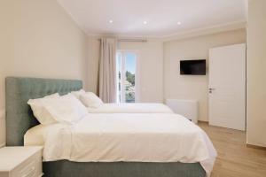 a white bedroom with two beds and a television at Villa Alena by Villa Plus in Kalami +22 photos