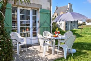 une table avec des chaises et un parasol sur une terrasse dans l'établissement LocaLise - Maison G5 au Guilvinec - A 50m de la mer avec jardin et piscine - Tout à pied, plages, port, centre, commerces, marché - Wifi inclus - Animaux bienvenus - Linge de lit inclus, au Guilvinec