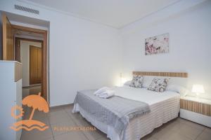 a white bedroom with a bed and a kitchen at Patacona Resort Apartments Primera Linea in Valencia