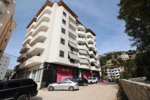 a white building with cars parked in front of it at Motra Apartment in Metogjashta