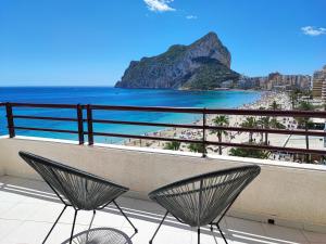 Un balcón con dos sillas y vista a la playa. en Apartamento Dúplex Aloha Calpe, primera línea de playa, en Calpe
