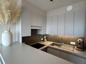 una cocina con armarios blancos y un jarrón con flores en la encimera en Studio Ribella West 5, en De Panne