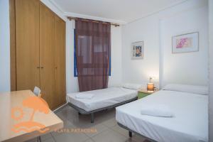 a room with two beds and a desk and a table at Patacona Resort Apartments Primera Linea in Valencia