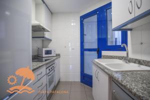 a kitchen with a sink and a blue door at Patacona Resort Apartments Primera Linea in Valencia