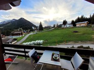 a balcony with a table and chairs and a view at Joli nid cosi à la montagne -Lécherette in Chateau-d'Oex