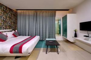 um quarto com uma cama grande e uma televisão em K Tree Boutique Hotel, Kolhapur em Colhapur