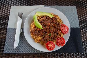 a plate of food with spaghetti and tomatoes on a table at NOAZ Hotel Kampala in Kampala