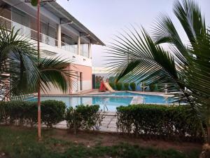 a house with a swimming pool and palm trees at Hotel Cajuína Sul in Teresina