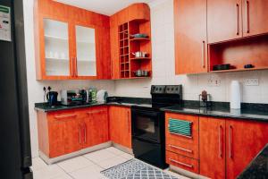 a kitchen with wooden cabinets and black appliances at LE The Lustrous Home in Gaborone