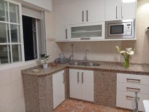 a kitchen with white cabinets and a sink and a microwave at Villa Merchy Combarro in Poio